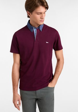 Bordeaux polo skjorte med en lyseblå mønstrede krave og hvidt logo. Korte ærmer, klassisk pasform og blødt bomuldsstof.