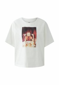 Witte t-shirt met korte mouwen met een centrale afgedrukte graphic van een persoon die eetstokjes vasthoudt, met een tafel vol voedsel op de achtergrond.