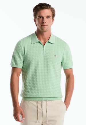 Lichtgroene polo met een gestructureerd patroon, korte mouwen en een halve ritssluiting. Bevat witte accenten en een klein logo op de linkerkant van de borst.
