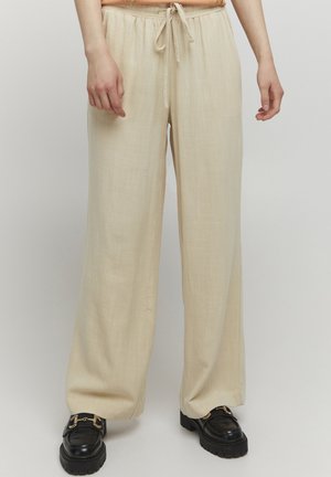 Pantalons larges beiges clairs en tissu texturé, dotés d'une taille élastique avec cordon de serrage et de coutures latérales pour plus de structure.