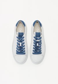 Bílé tenisky s hladkým koženým svrškem, modrými džínovými detaily na jazyku a tkaničkách, s kulatou špičkou a strukturovanou gumovou podrážkou.