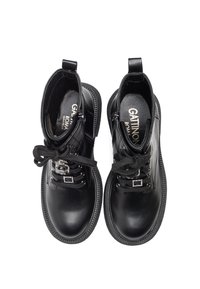 Black leather ankle boots with round toes, flat soles, decorative laces, and silver hardware accents, featuring a branded insole.