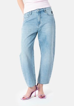 Light blue denim jeans with a straight-leg fit, featuring a button closure, belt loops, and subtle fading; paired with strappy pink heels.