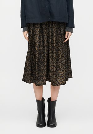 Γυναίκα που φοράει φούστα με μήκος μέχρι τα γόνατα σε μοτίβο λεοπάρ, συνδυασμένη με μαύρα μποτάκια αστραγάλου και σκουρόχρωμο μπουφάν με εμφανείς γκρι μανσέτες.