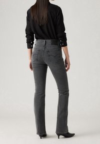 Säästävän mittapituuden, korkeavyötäröiset harmaat farkut, joissa on kevyt levennys, viisi taskua ja näkyvä logo-tägi takavyötäröllä. Rakenne denim-materiaali.