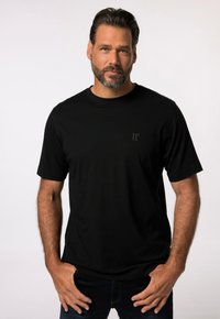 Sort bomuld t-shirt med korte ærmer, der har et diskret logo på brystet. Slim fit og glat tekstur. Kombineret med mørke jeans.
