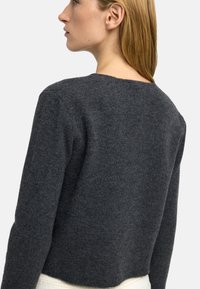 Szary wełniany sweter z okrągłym dekoltem, długimi rękawami i dopasowanym krojem. Miękka struktura, minimalistyczny design i brak widocznych wzorów.