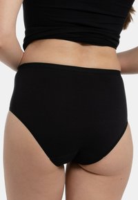 Culotte haute noire en coton doux, avec une taille lisse et sans coutures visibles à l'arrière pour plus de confort et un bon ajustement.