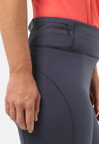 Leggings taille haute en navy fabriqués dans un tissu lisse et extensible. Équipés d'une poche zippée discrète et de détails de couture courbés.