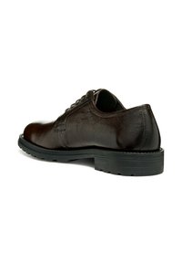 Zapato de cuero marrón oscuro con punta redonda, textura suave, detalles cosidos y suela gruesa de goma negra. Muestra una vista lateral y trasera.