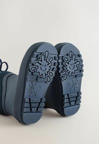 Marina gummistövlar har strukturerade sulor med lekfulla plask- och smiley-ansiktsmotiv, vilket gör dem lämpliga för blöta förhållanden.