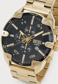 Orologio in acciaio inossidabile con finitura dorata e quadrante nero, con funzionalità cronografo, audaci indici delle ore dorati e display della data alle tre.
