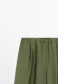 Olijfgroene broek met een elastische tailleband en plooien aan de voorkant, gepresenteerd tegen een effen witte achtergrond.