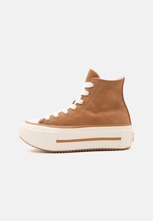 Baskets montantes marron avec semelle plateforme blanche épaisse et lacets blancs, vues de profil sur un fond clair uni.