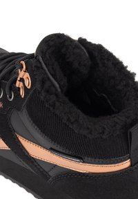 Černé tenisky s texturovaným svrškem, měkkou fleecovou podšívkou a měděnými akcenty. Design zahrnuje polstrovaný límec a zesílené dírky na tkaničky.