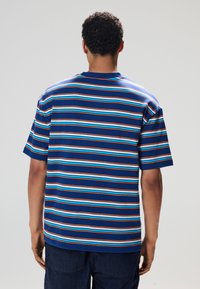 Blå kortærmet t-shirt med horisontale striber i orange og lyseblå. Lige snit, rund halsudskæring og blød stoftekstur.