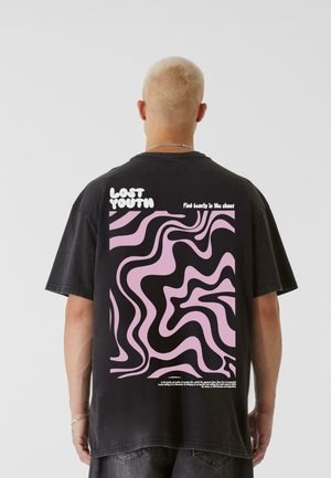 Fekete, oversized póló, a hátsó oldalán hullámos rózsaszín és fekete grafikai mintázattal, a minta felett a "LOST YOUTH" felirattal.