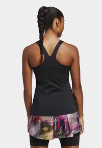 Zwarte sportieve tanktop met racerback ontwerp. Voorzien van een kleurrijke, gevarieerde gelaagde mesh rok met bloemenmotieven. Gladde textuur en aansluitende stijl.
