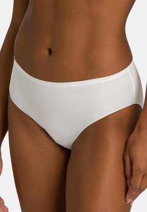 Nahaufnahme einer Person, die schlichte weiße hochgeschnittene Unterwäsche trägt, mit sichtbar Taille, Hüften und oberem Oberschenkelbereich.