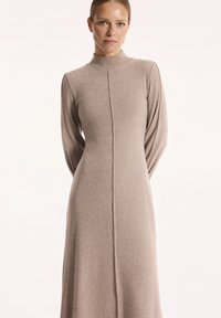 Długo rękawowa, taupe'owa sukienka uszyta z miękkiego materiału. Posiada wysoki dekolt oraz centralny szew biegnący od szyi do dołu. Prosty i elegancki design.