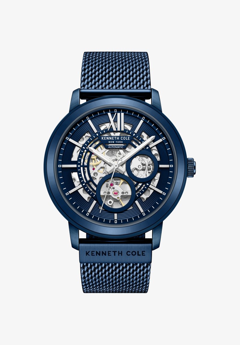 Montre-bracelet automatique Kenneth Cole bleue avec bracelet en maille, cadran squelette révélant les engrenages internes, et chiffre romain XII argenté en haut.