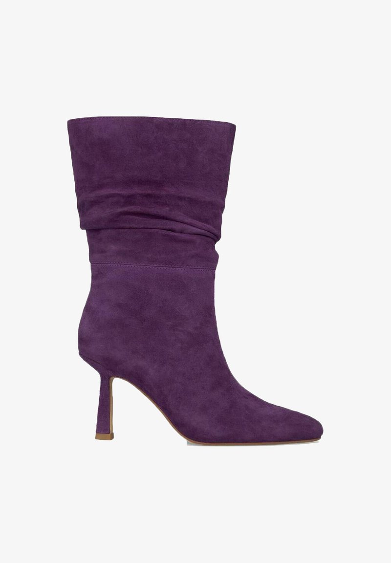 Botte de cheville en suede violet avec un design fluide, bout pointu et talon aiguille fin. Texture lisse et embellissements minimalistes.