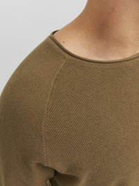 Sweter z dzianiny w oliwkowej zieleni, posiada okrągły dekolt i fakturowane przeszycia. Rękawy mają design raglanowy, a na dekolcie znajduje się gładkie wykończenie.