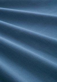 Textil egy puha, texturált kék anyagból, finom szőtt mintával, lágy redőkkel és sima felülettel.