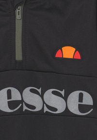 Schwarzer Pullover mit einem Halb-Reißverschluss, ausgestattet mit einem Logo-Patch in Orange und Rot sowie großen grauen Schriftzügen auf der Vorderseite. Glatte Stoffstruktur.