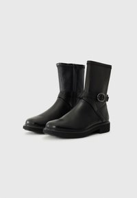 Black ankle boots made of smooth leather with a chunky rubber sole, zip closure, and a decorative strap with a buckle detail.