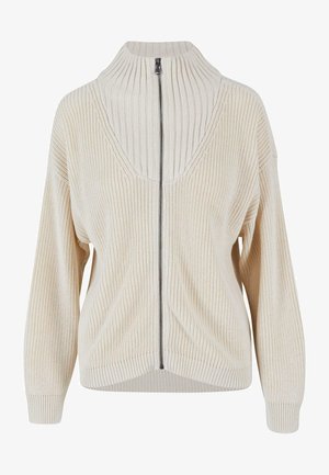 Maglione beige lavorato a maglia con colletto alto e chiusura a zip. Presenta maniche ampie, texture a coste e scollatura a V.