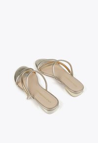 Metalliska silverfärgade slidesandaler med dubbla remmar och en ögla-design. Slät läderstruktur med en fyrkantig klack och beige innersula. Guld logotypdetalj.