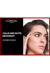 L'Oréal produktreklam som visar en kvinna med medellångt mörkt hår, neutral sminkning och en märkbar textur på huden.