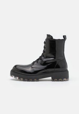 Bottine noire brillante à lacets jusqu'à la cheville avec semelle épaisse et languette à tirer, dotée d'un intérieur doublé en shearling pour la chaleur.
