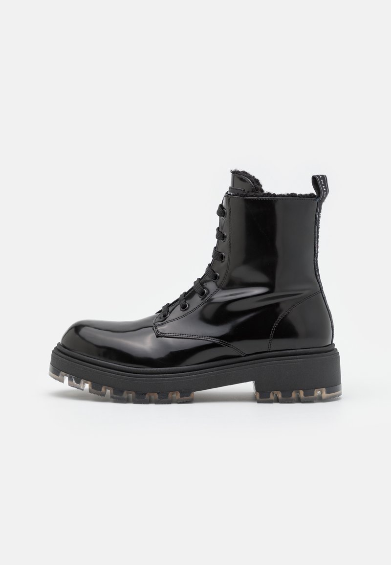 Bottine noire brillante à lacets jusqu'à la cheville avec semelle épaisse et languette à tirer, dotée d'un intérieur doublé en shearling pour la chaleur.