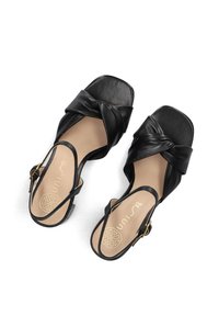 Zwarte leren sandalen met een gedraaid ontwerp aan de voorkant, open achterkant en vierkante neus. Voorzien van een dunne enkelband en een beige binnenzool met branding.