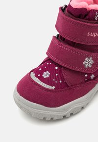 Stivale viola in suede con fodera rosa, dotato di due fasce in Velcro, motivi a fiocco di neve e suola in gomma grigia texturizzata.