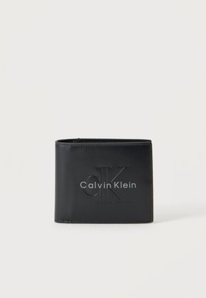 Sort læder Calvin Klein bifold tegnebog med præget "cK" logo og sølv mærkenavn foran mod hvid baggrund.