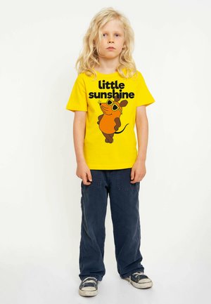 Yellow t-shirt with "little sunshine" text and cartoon mouse graphic, paired with dark blue pants and worn sneakers. Casual outfit.