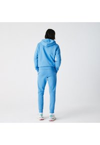 Lichtblauwe hoodie en bijpassende joggers van zacht materiaal, met een relaxte pasvorm, geribbelde boorden en een capuchon met trekkoord.
