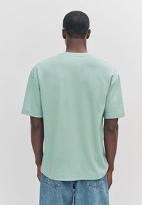 Muntgroen T-shirt met korte mouwen, een ronde hals en een losse pasvorm. Gemaakt van zacht materiaal, met een effen ontwerp zonder zichtbare logo's of accenten.
