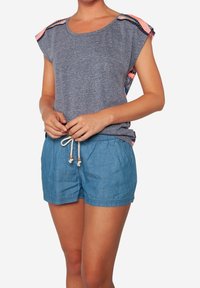 Camisa gris de manga corta con acentos de hombros estampados, combinada con pantalones cortos de tiro alto en azul claro con cordón, que presentan una textura suave y un ajuste relajado.