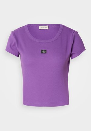 Lilla, ribbet t-skjorte med kort erme som har rund hals og en liten svart Calvin Klein-logo på brystet. Myk tekstur.