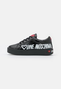 Svarta lackskinnssneakers med tjock svart sula. Har vit "LOVE MOSCHINO" text och röda hjärtan på hälen.