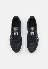 Černé běžecké boty s texturovaným svrškem, bílým logem swoosh a QR kódem na jazyku. Lehký design s bílou mezipodešví a gumovou podešví.