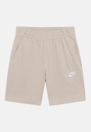 Smėlio spalvos sportiniai šortai iš minkštos medžiagos, turintys elastingą juosmenį, dvi šonines kišenes ir baltą Nike logotipą ant kojos.