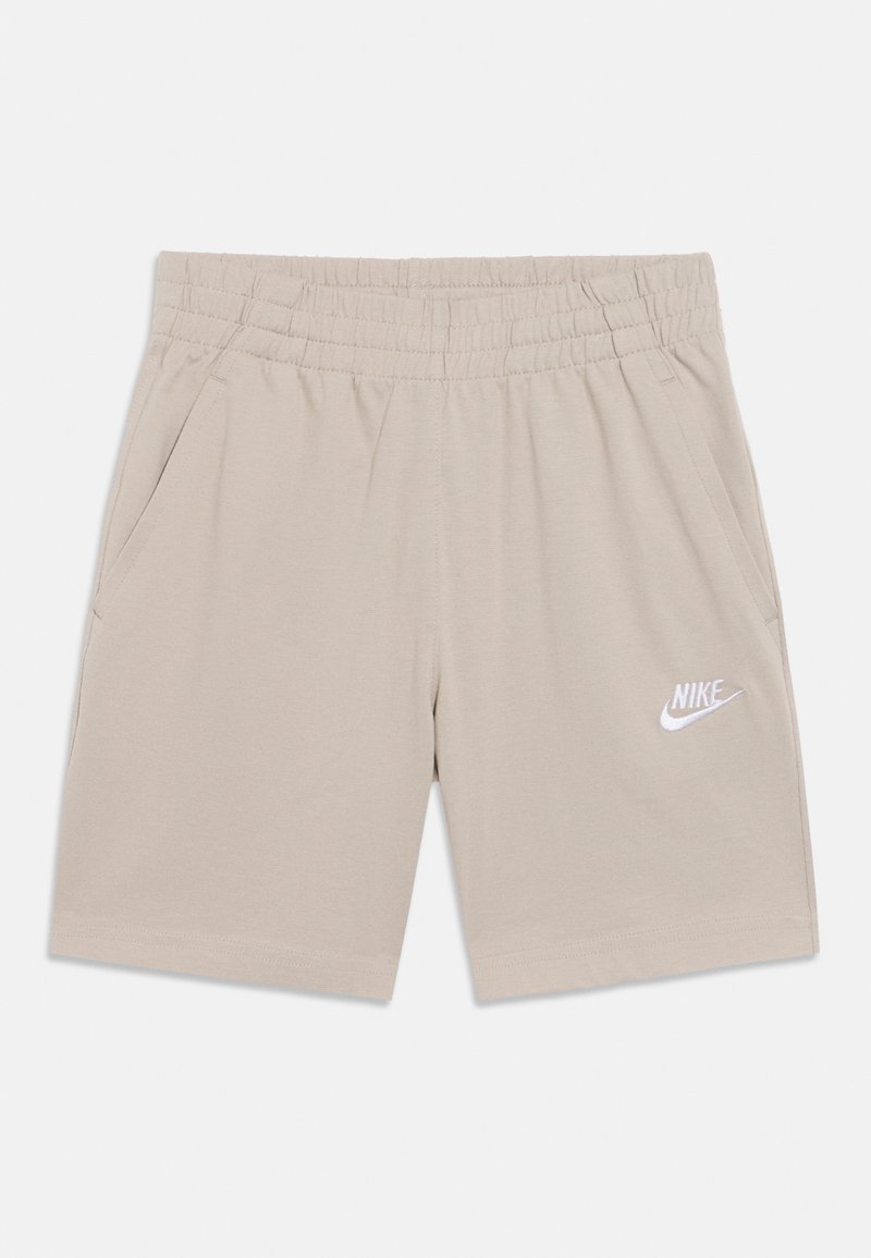 Shorts de sport beiges en tissu doux, avec une ceinture élastique, deux poches latérales et un logo Nike blanc sur la jambe.