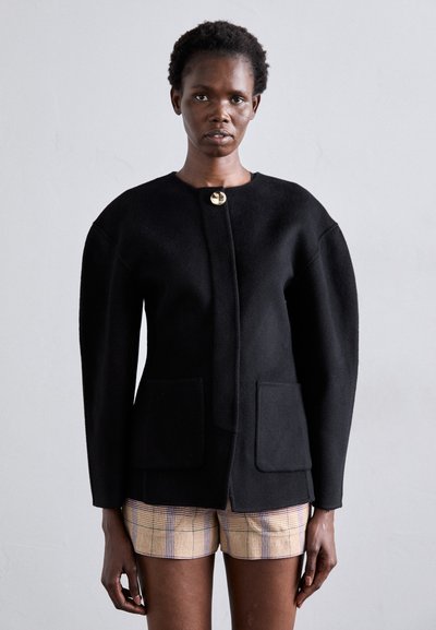 Blazer de lana negra con escote redondo, grandes bolsillos frontales y cierre de botón dorado. Presenta hombros estructurados y una silueta ajustada.