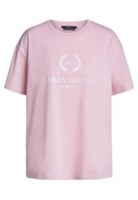 Růžové bavlněné tričko s volným střihem, krátkými rukávy a výstřihem do kulata. Grafika zahrnuje nápis "URBAN DELUXE" a design vavřínového věnce.