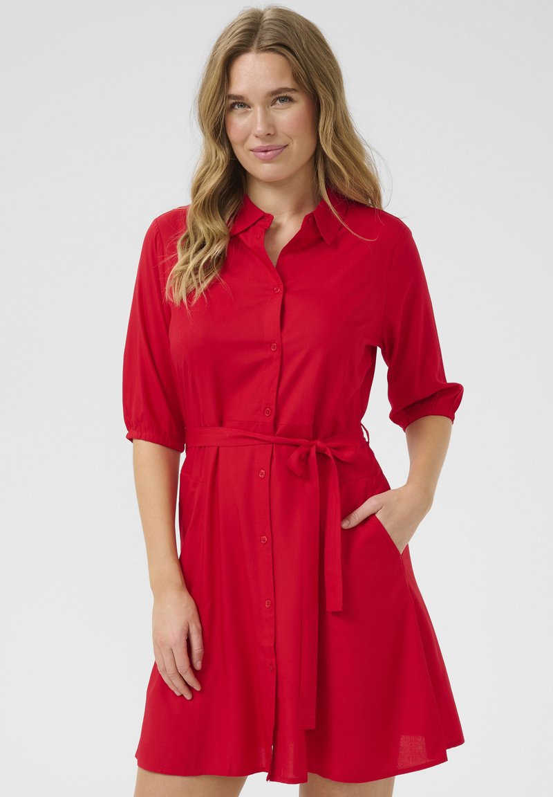 Kerge kangast punane särgikleid, millel on nööpide jaotusega esiosa, krae, lühikesed varrukad, seotud vöö ja küljetaskud.